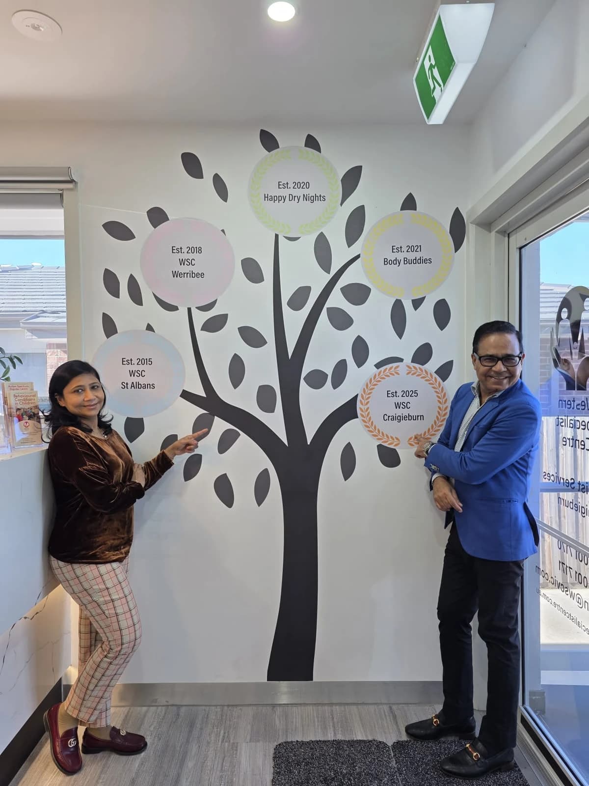 Two people beside the Western Specialist Centre history tree